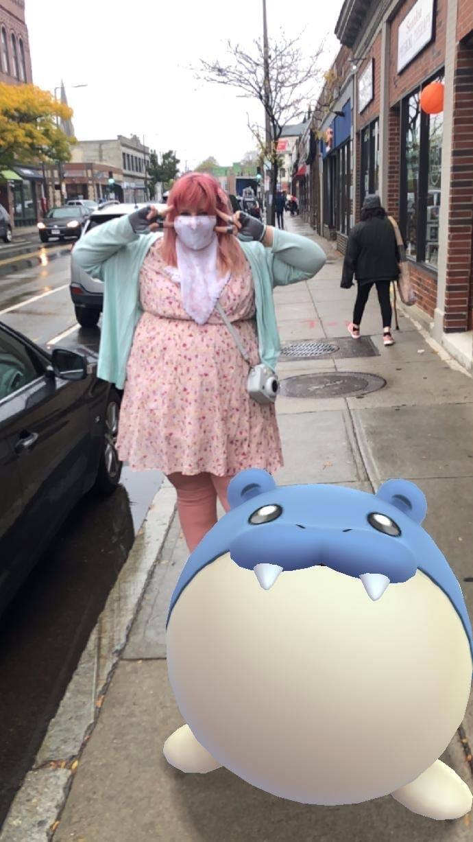 Allison is standing on the street, wearing a pretty floral dress, in front of her a digital animal is adorbing heavily
