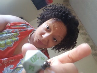 Bridgett holding a d20 peering mysteriously into the camera.